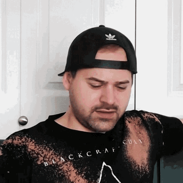 a man wearing a black hat and a black shirt that says blackcraft-cult