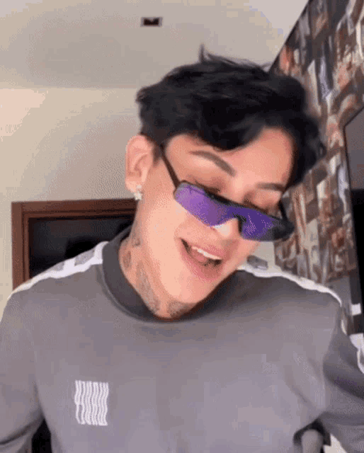 a young man wearing purple sunglasses and a grey shirt with the letter r on it