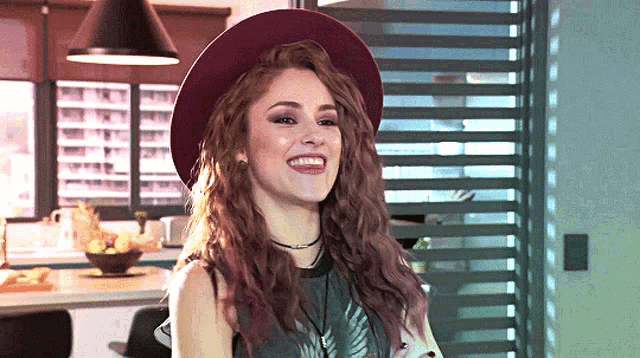 a woman wearing a purple hat and a black shirt smiles
