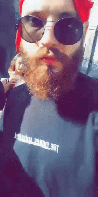 a man with a beard wearing sunglasses and a black shirt that says ' lme ' on it