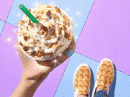 a person is holding a cup of coffee with whipped cream and a straw .