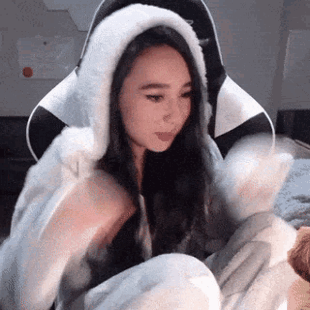 a woman is sitting in a chair wearing a bunny costume and a furry hood .