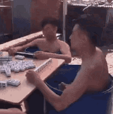 a shirtless man is playing a game of dominoes while sitting in a tub .