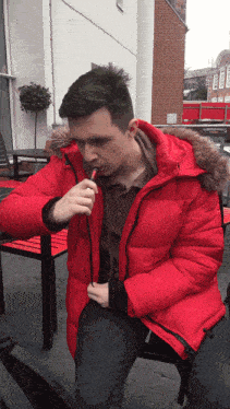 a man in a red jacket smoking a cigarette