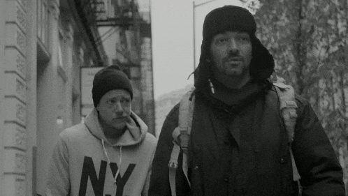 a man wearing a ny sweatshirt walks down the street
