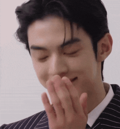 a close up of a man in a suit covering his mouth with his hands