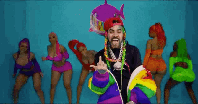a man in a rainbow jacket is standing in front of a group of women .