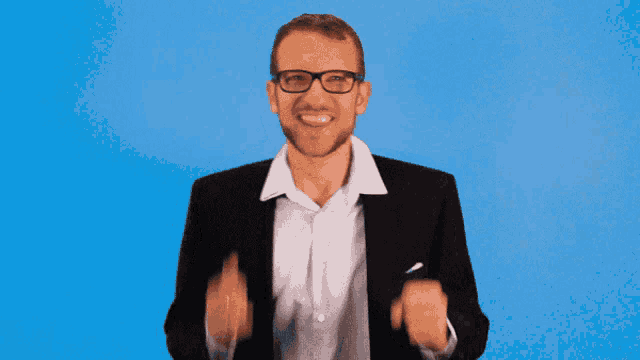 a man wearing glasses and a suit is making a victory sign
