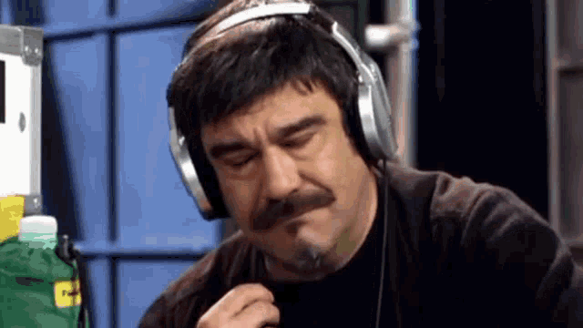 a man with a mustache wearing headphones and a cigarette in his mouth .