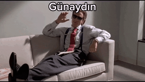 a man in a suit and tie is laying on a couch with the words günaydin written on the bottom