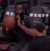 a man with a beard is sitting in a stadium with a basketball .