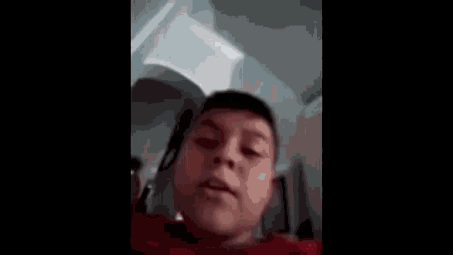 a young boy in a red shirt is making a funny face in a bathroom .