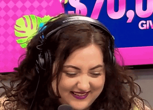 a woman wearing headphones is smiling in front of a screen that says ' gn '