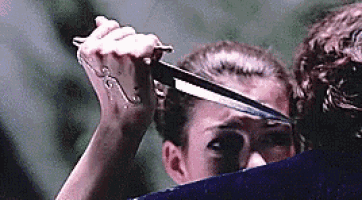a woman is holding a knife in her hand and cutting a man 's hair .