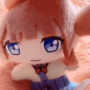 a stuffed doll of a girl with blue eyes is sitting on a bed .