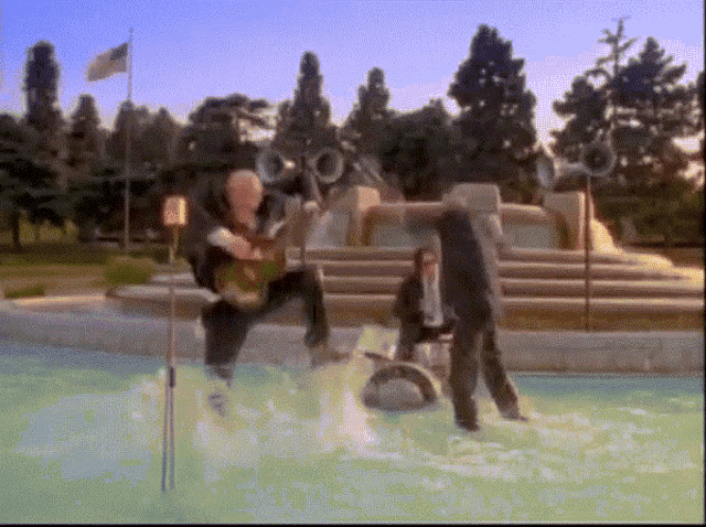 a man in a suit is standing in a pool with a camera