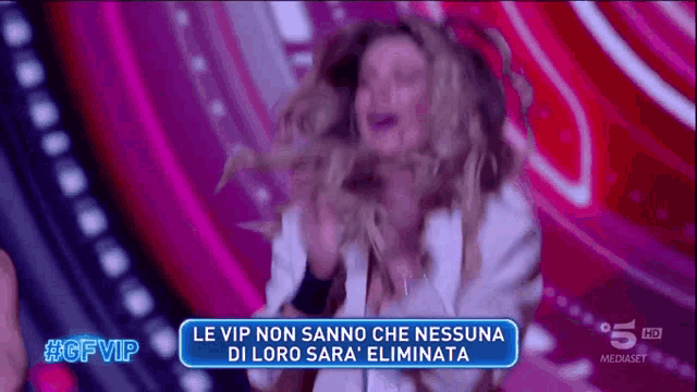 a woman is dancing on a stage with a sign that says le vip non sanno che nessuna di loro sara eliminata
