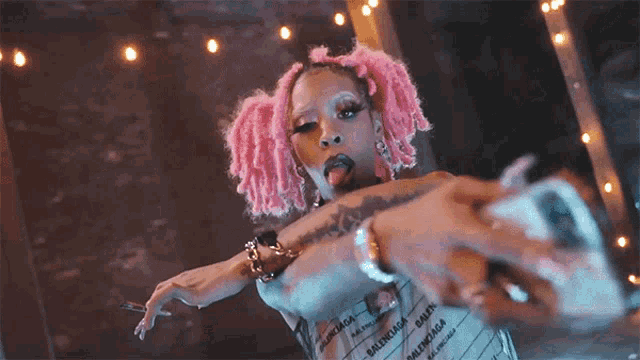 a woman with pink hair is taking a picture with her phone