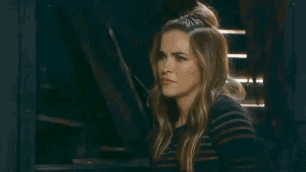 a woman in a striped shirt is making a funny face while looking out of a window .