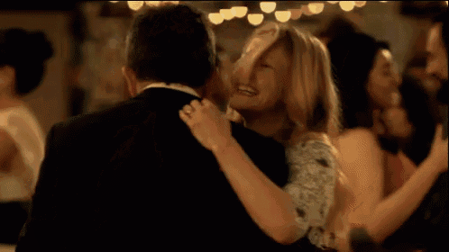a man and woman are dancing together and the woman is laughing .