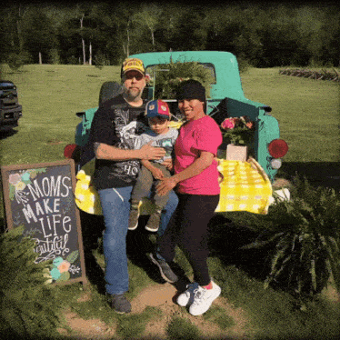 a family standing in front of a truck with a sign that says " moms make life beautiful "