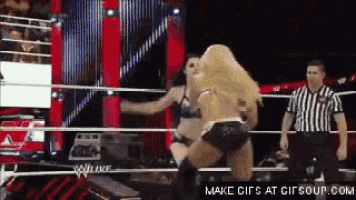 two women wrestling in a ring with a referee in the background