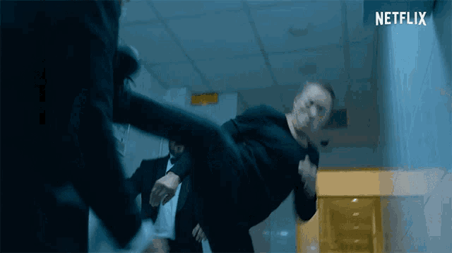 a man kicking another man in the face with a netflix logo behind him