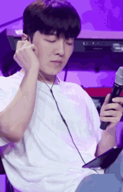 a man wearing headphones and holding a microphone is sitting in front of a piano .