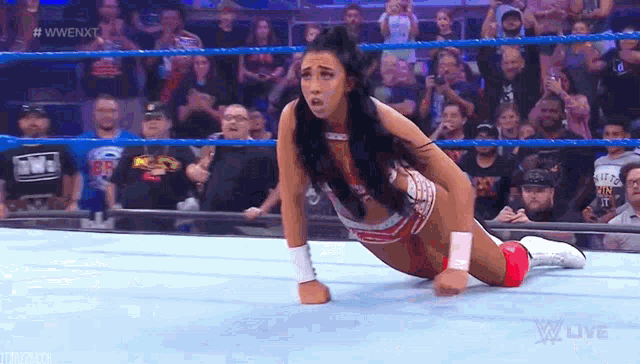 a female wrestler is laying on the floor in a wrestling ring .