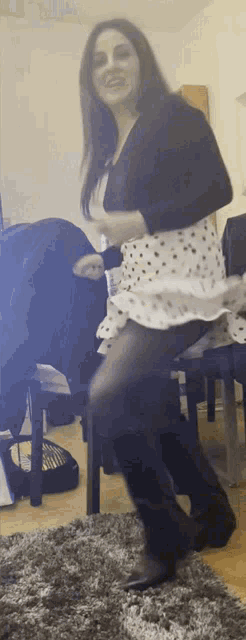 a woman in a polka dot dress and black boots is dancing on a rug