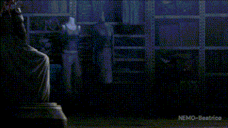 a woman in a white dress is kneeling in front of a statue in a dark room .