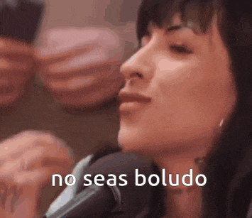 a woman is sitting in front of a microphone with the words no seas boludo on her face .