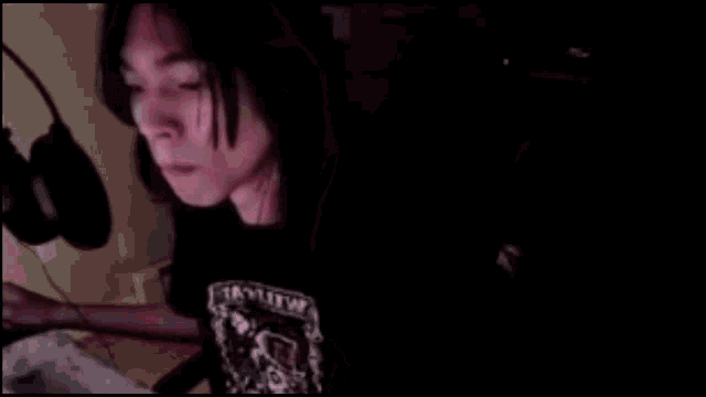 a person is making a funny face while wearing headphones and a black shirt with a skull on it .