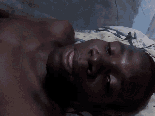 a man without a shirt is laying on a bed with his eyes closed