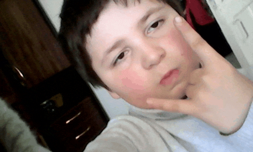a young boy is making a peace sign with his hand