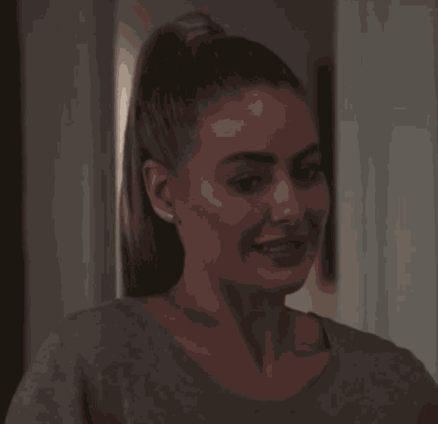 a woman with a ponytail is smiling and wearing earrings