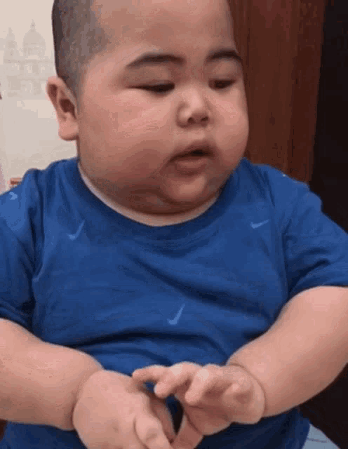 a baby in a blue shirt is making a funny face