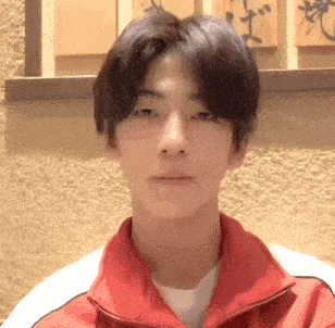 a young man is wearing a red jacket and a white shirt .