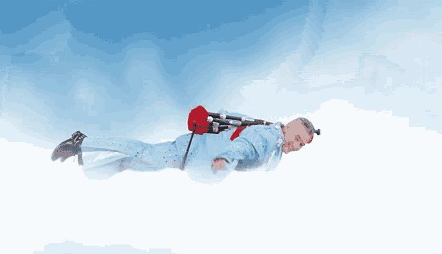 a man in a blue suit is flying through the air with a red bag on his back