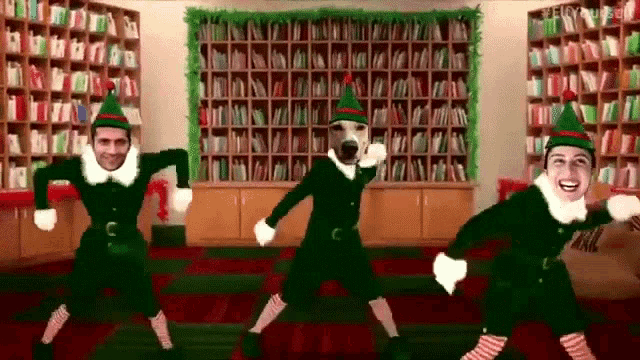 three people dressed as elves are dancing in front of a library