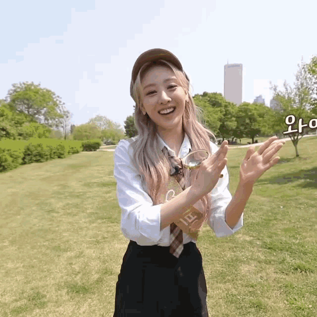 a girl wearing a hat and a tie is standing in a park
