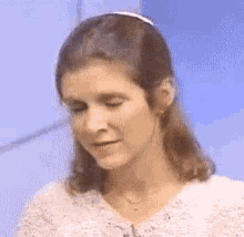 a close up of a woman 's face with her eyes closed wearing a white headband .