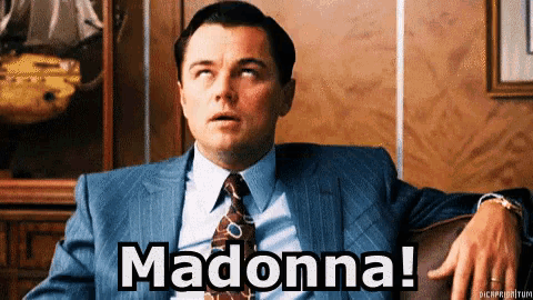 a man in a suit and tie is sitting in a chair and says madonna