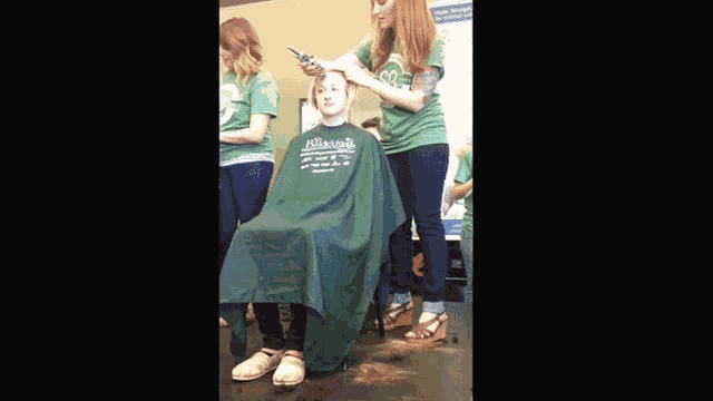 a girl is getting her hair cut by a woman wearing a green shirt that says " allison "