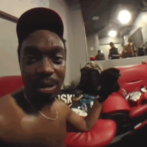 a shirtless man wearing a hat with the word sk on it sits in a boxing ring
