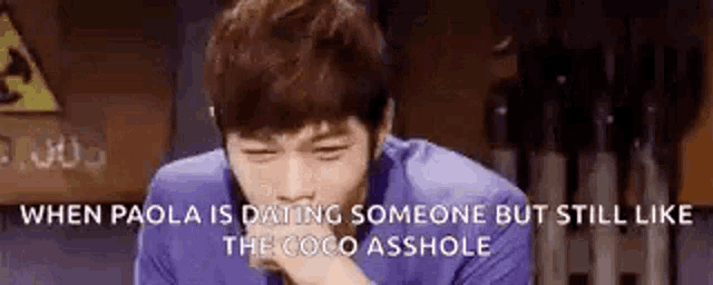 a man is laughing and covering his mouth with his hand while a quote is behind him .