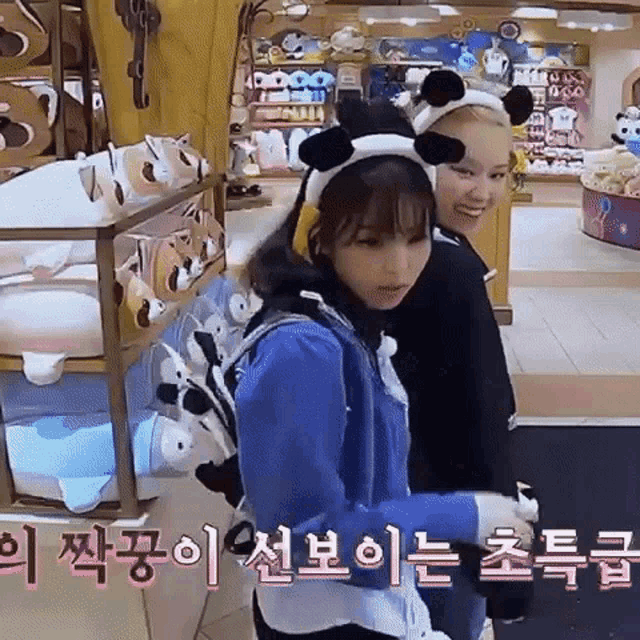 two girls wearing panda ears are standing next to each other in a store with korean writing .