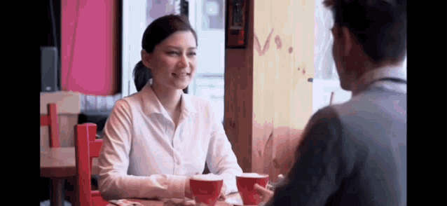a man and a woman are sitting at a table talking to each other .