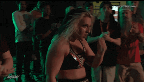 a female wrestler is standing in front of a green light with the words watchdpw on the bottom right