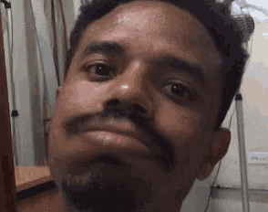 a man with a beard is making a funny face and looking at the camera .